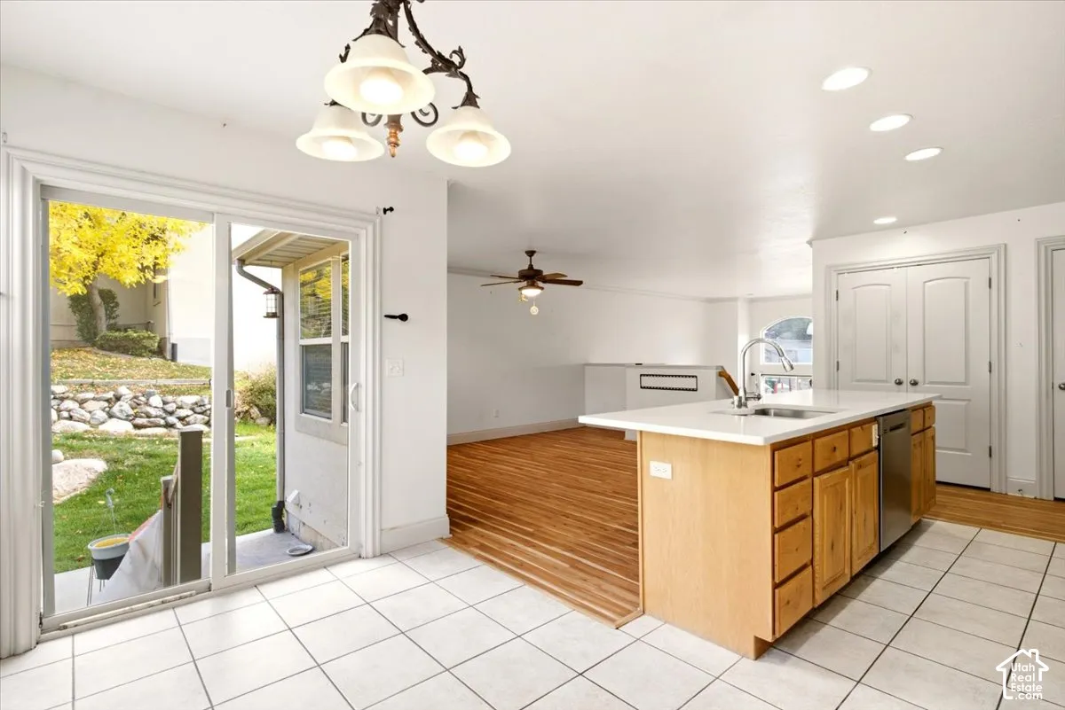 Kitchen featuring a center island with a stainless steel sink, wood-finish cabinetry, sliding glass doors, tiled flooring, and recessed lighting