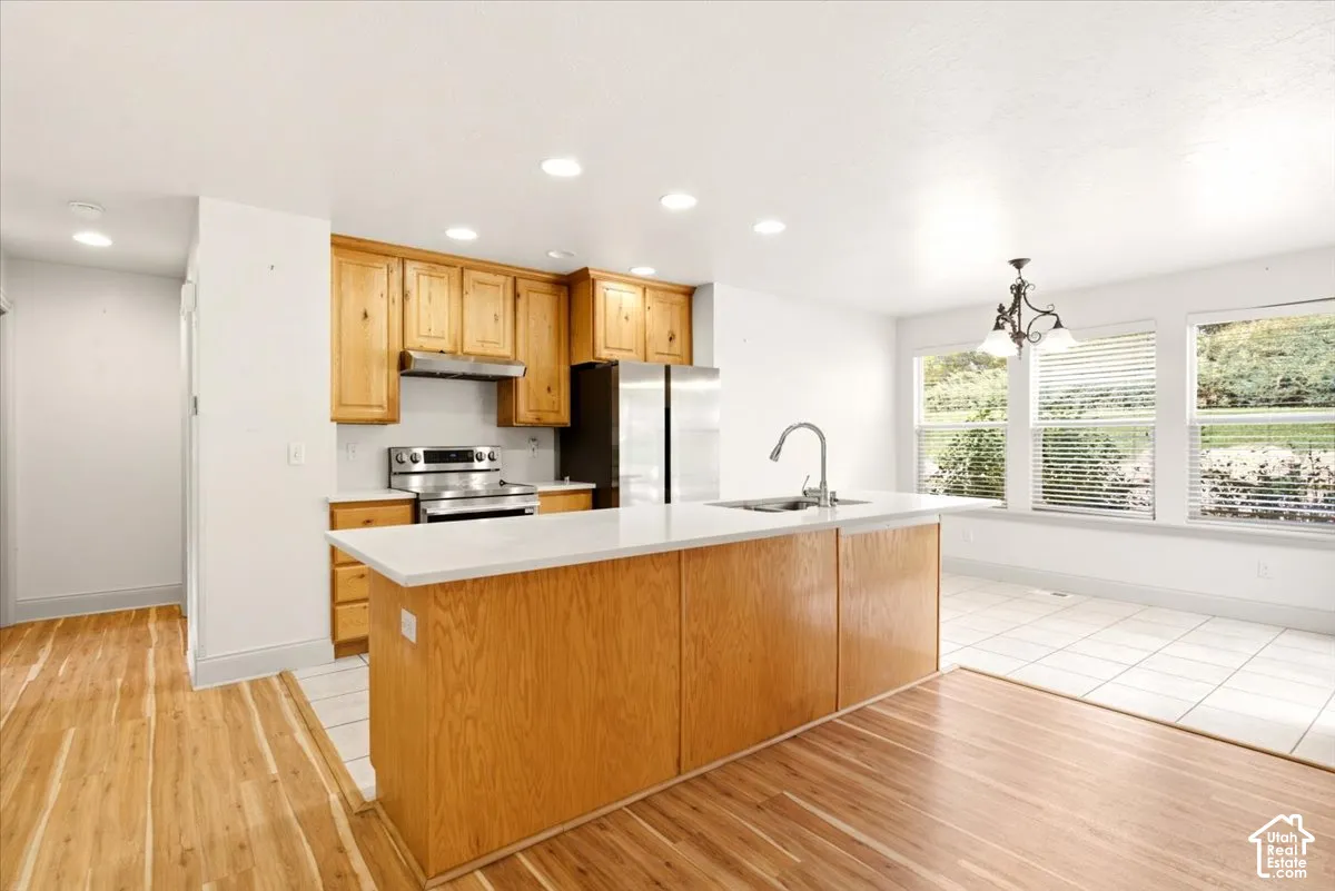 Kitchen featuring wood cabinetry, a central island with a solid-surface countertop, stainless steel appliances, recessed lighting, and tile flooring