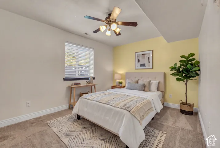 Room featuring neutral wall tones, a bold yellow accent wall, carpeting, a ceiling fan with integrated lighting, and a window with horizontal blinds