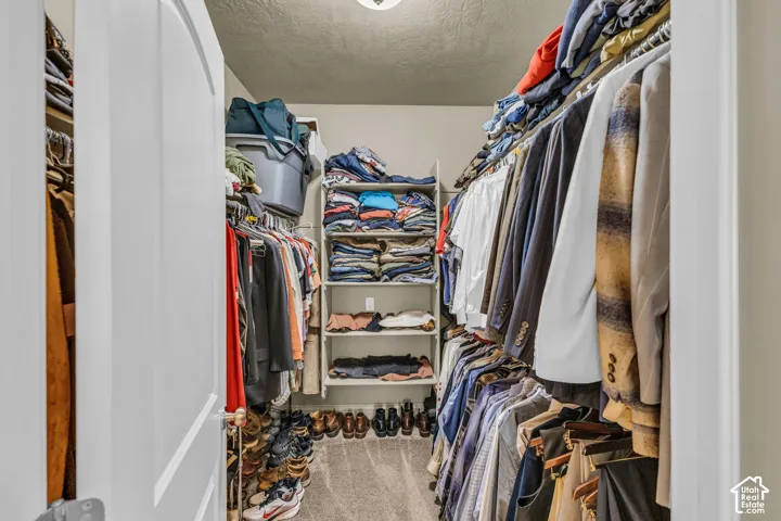 Walk-in closet featuring multi-tiered hanging rods and integrated wall-mounted shelving
