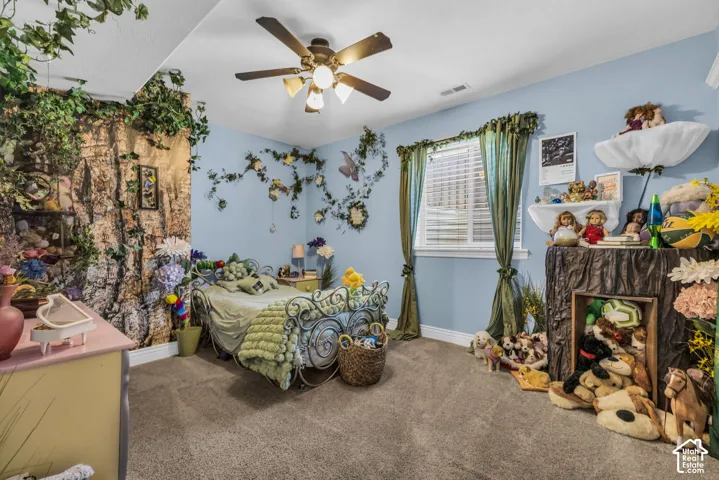 Interior room featuring neutral carpeting, a central multi-blade ceiling fan with integrated lighting, and a single-pane window