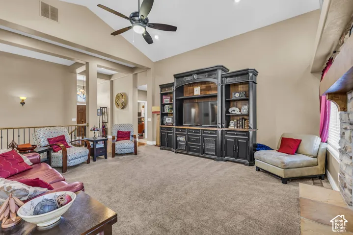 Vaulted ceilings featuring a central overhead fan, custom built-in cabinetry, and a floor-to-ceiling stone-faced fireplace