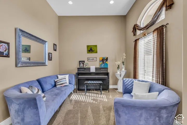 High-ceiling room featuring carpeting, recessed lighting, and an arched window