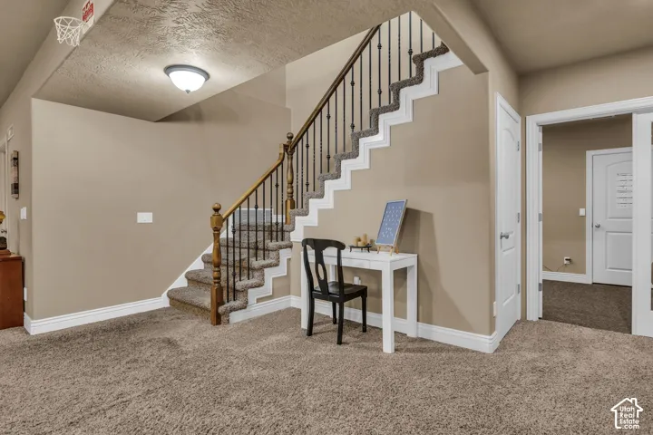 Staircase featuring a stained wood handrail, metal balusters, and carpeted treads, complemented by two-panel interior doors and a flush-mount ceiling light fixture