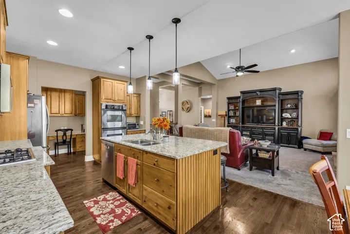 Kitchen featuring a center island with stone countertops, wood-finish cabinetry, stainless steel double wall ovens, recessed lighting, and wood-finish flooring