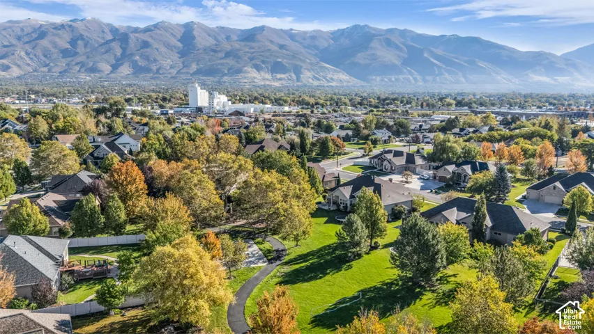 Aerial perspective featuring expansive mountain backdrops, paved walking paths, and mature deciduous trees throughout the neighborhood