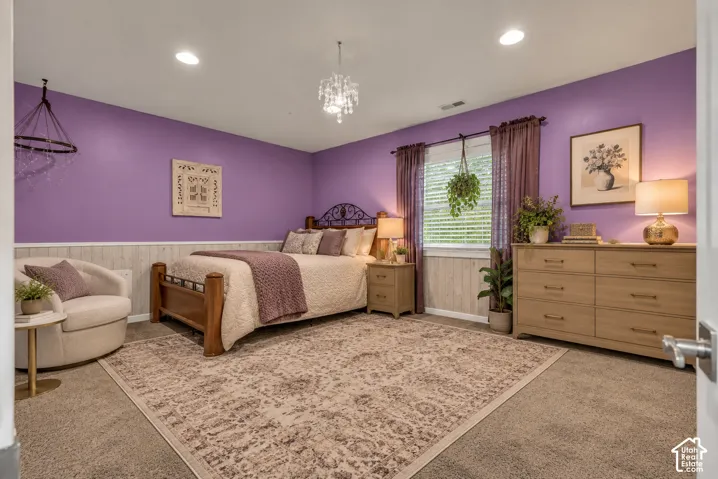 Bedroom featuring wood-paneled wainscoting, recessed ceiling lighting, a crystal chandelier, and carpeted flooring