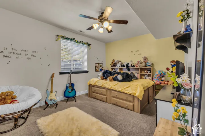 Neutral wall tones with a contrasting accent wall, carpeted flooring, and a multi-blade ceiling fan with integrated lighting