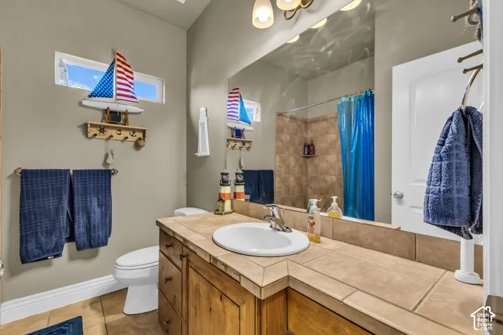 Bathroom featuring a vanity with tile countertop and backsplash, undermount sink, ceramic tile flooring, and a shower-tub combination with tiled surround