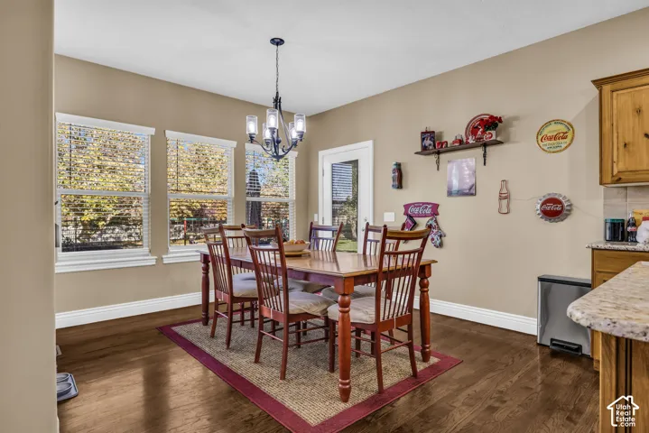 Dining area featuring wood-finish flooring, three large windows, a decorative chandelier, and a glass-paneled exterior door