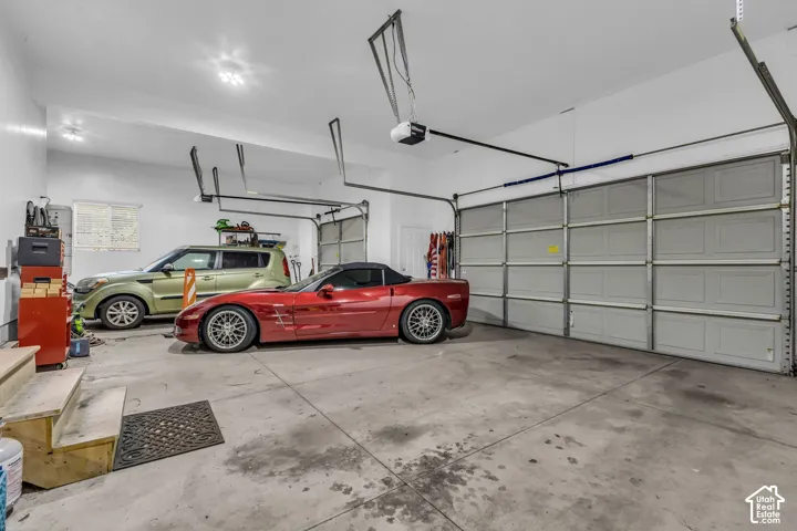 Spacious multi-car garage featuring a smooth concrete floor, high ceilings, automated door openers, and finished interior walls