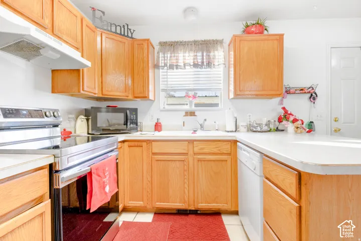 Kitchen featuring natural wood cabinetry, white countertops, a stainless steel range, and an integrated dishwasher