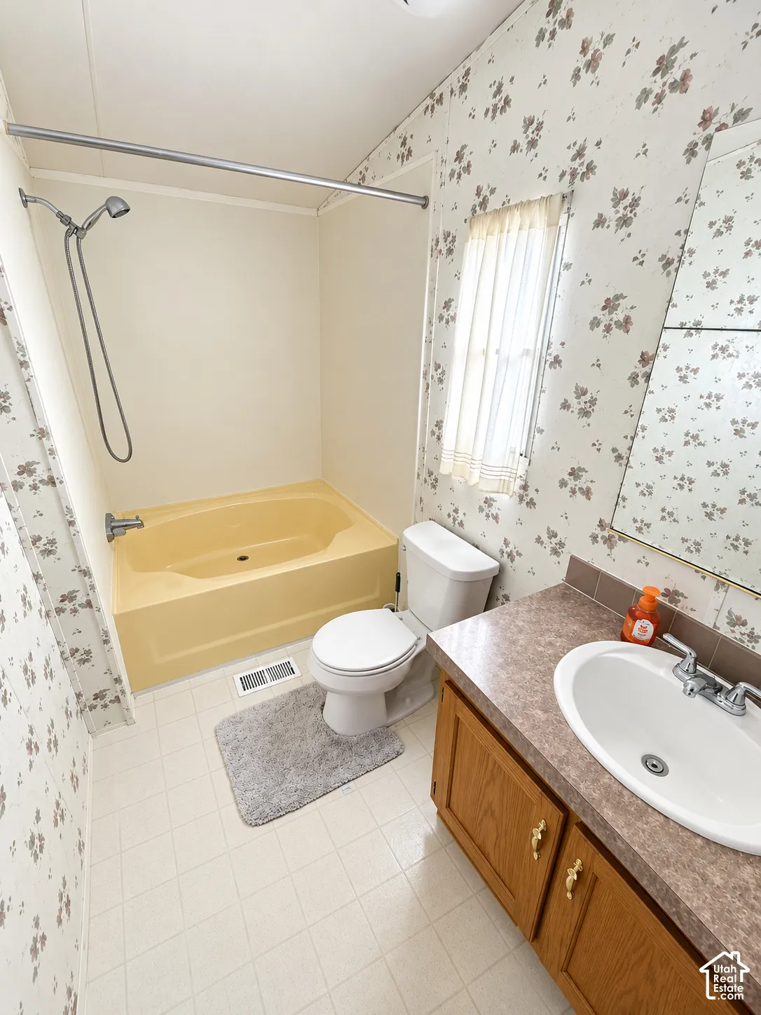 Bathroom featuring a soaking tub, wood-finish vanity cabinetry, laminate countertop with integrated oval sink, and a wall-mounted mirror