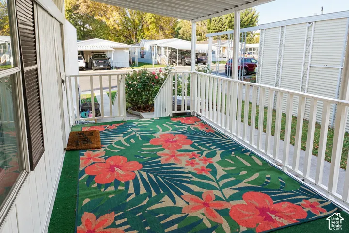 Covered porch featuring white metal railings, vertical siding, and shutter-trimmed windows