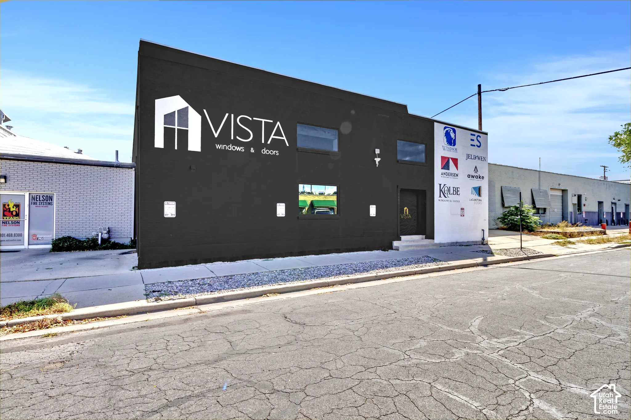 Commercial structure featuring a dark-toned facade, flat roofline, multi-pane fenestration, and asphalt-paved street frontage