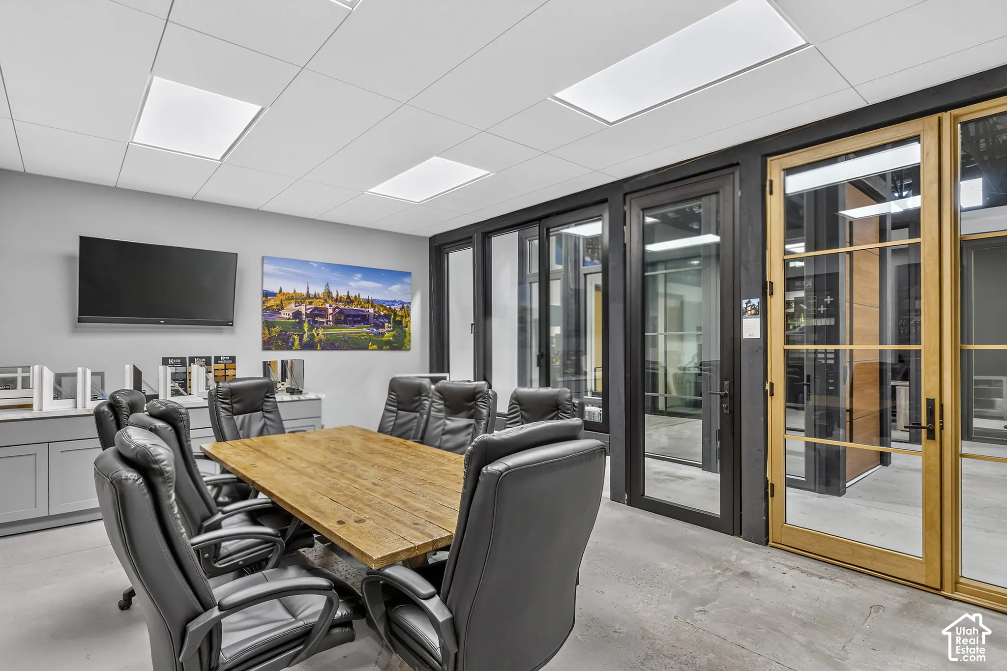 Interior space featuring drop ceiling with recessed lighting, concrete flooring, built-in cabinetry, and full-height glass doors with wood and metal frames