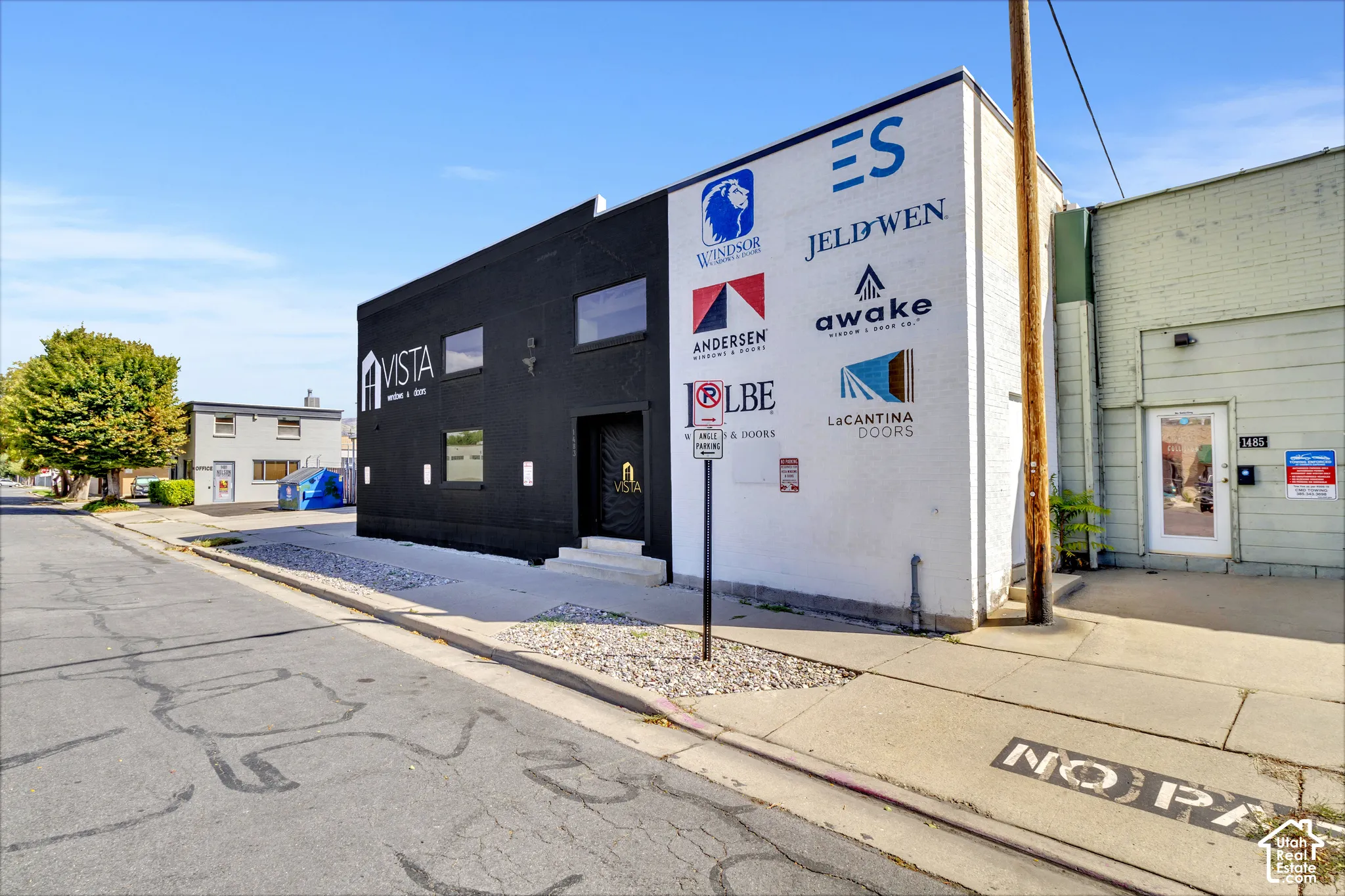 Commercial property exterior featuring a painted masonry facade, street-level entrance, rectangular window openings, and gravel landscaping