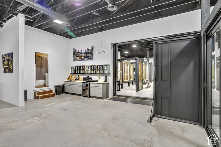 Industrial-style space featuring exposed painted ceiling, polished concrete flooring, built-in cabinetry with integrated under-counter refrigeration, and a large-format metal sliding door system