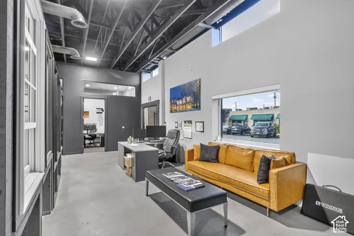 Industrial-style space featuring high vaulted ceilings with exposed ductwork, concrete flooring, expansive window lines, and clerestory windows