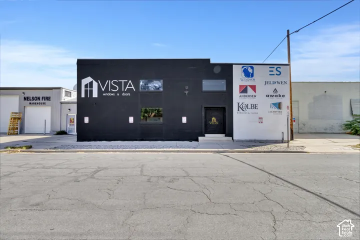 Commercial property featuring a matte black facade, multiple inset windows, and a paved street-level entrance
