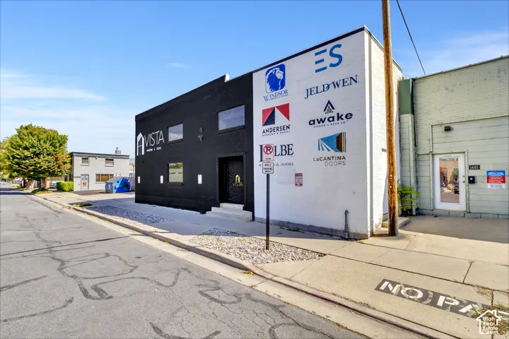 Commercial property exterior featuring a painted masonry facade, street-level entrance, rectangular window openings, and gravel landscaping