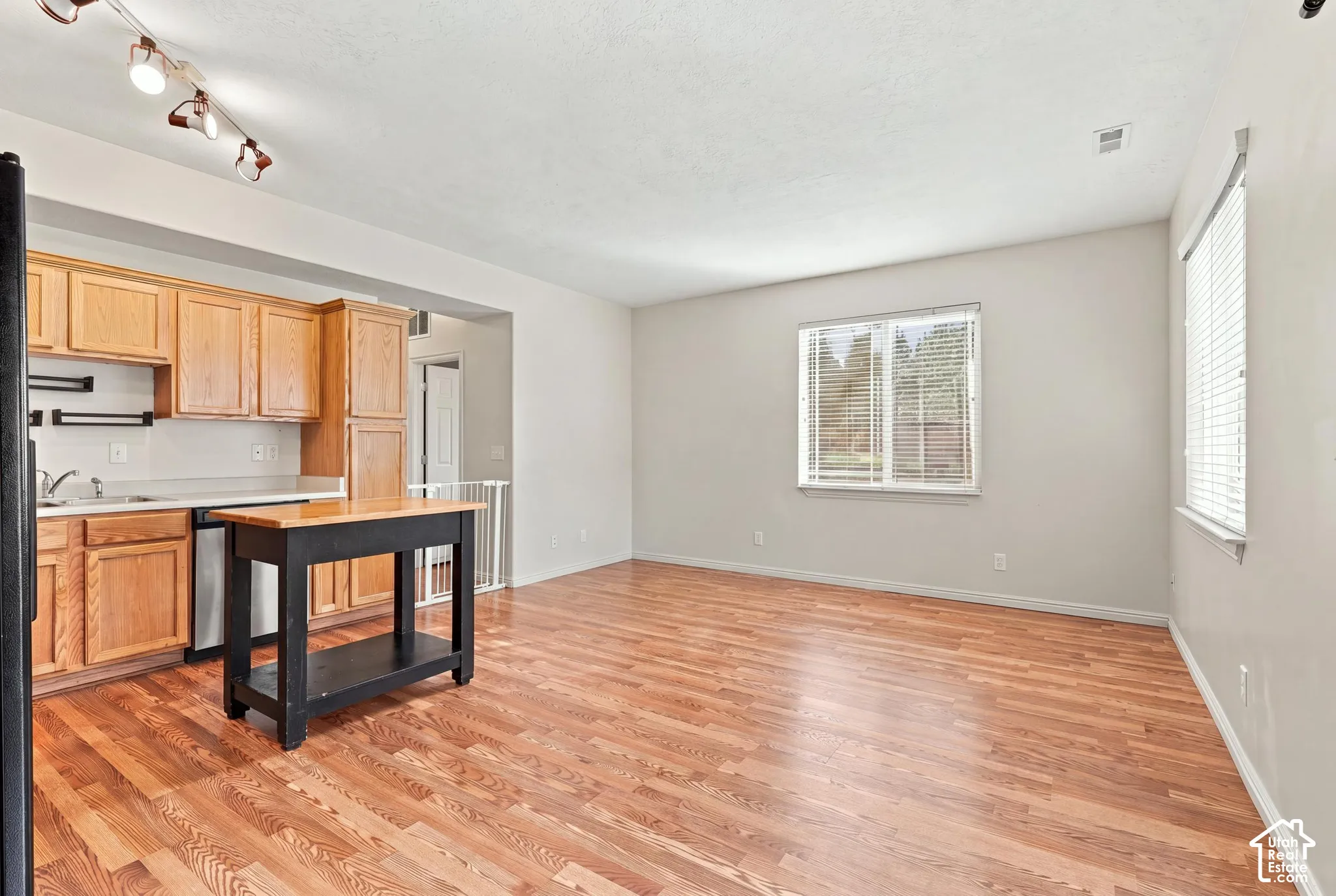Kitchen featuring wood cabinetry, stainless steel dishwasher, and wood-finish flooring throughout the space