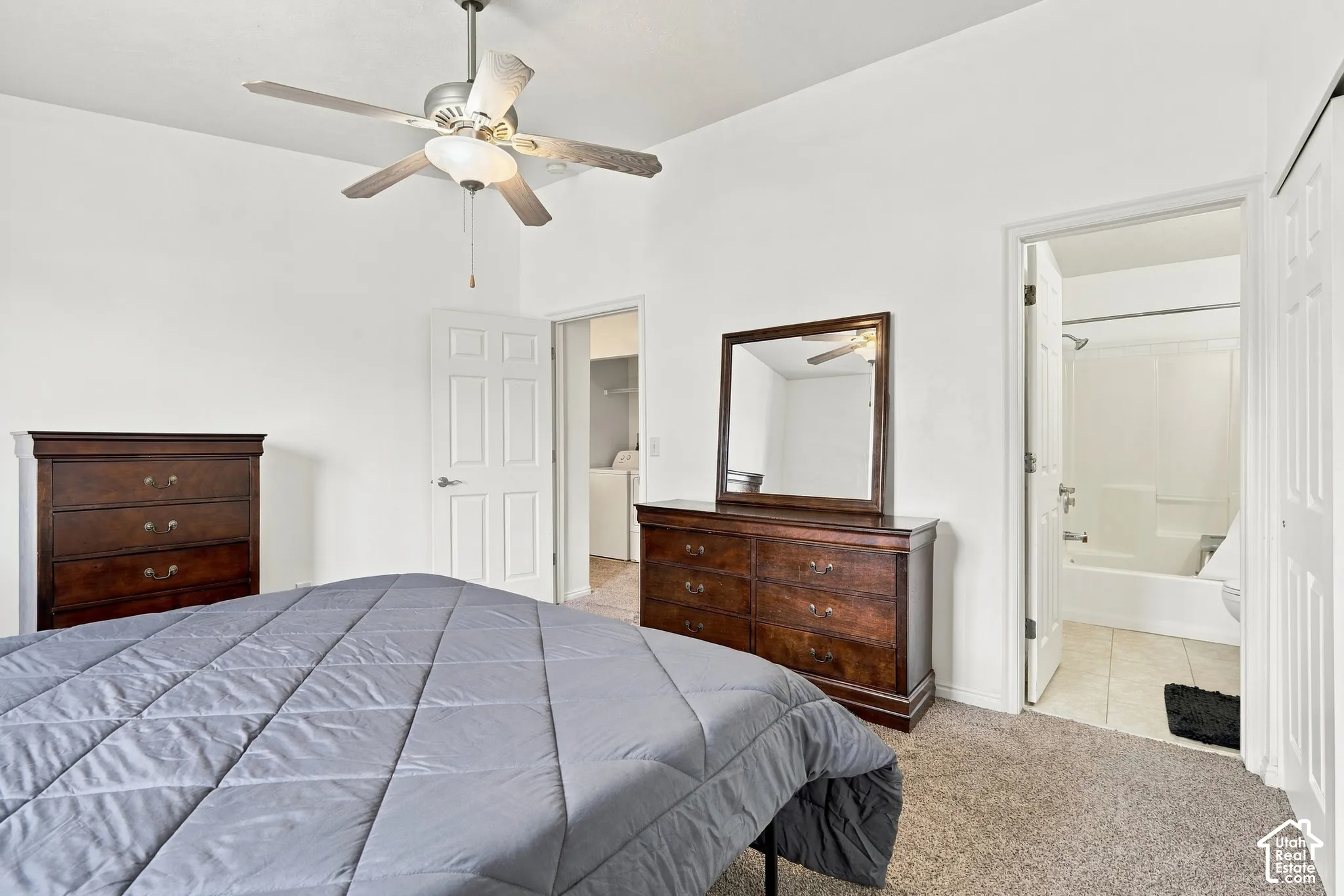 Room featuring neutral carpeting, a ceiling fan with light fixture, and panel-style interior doors