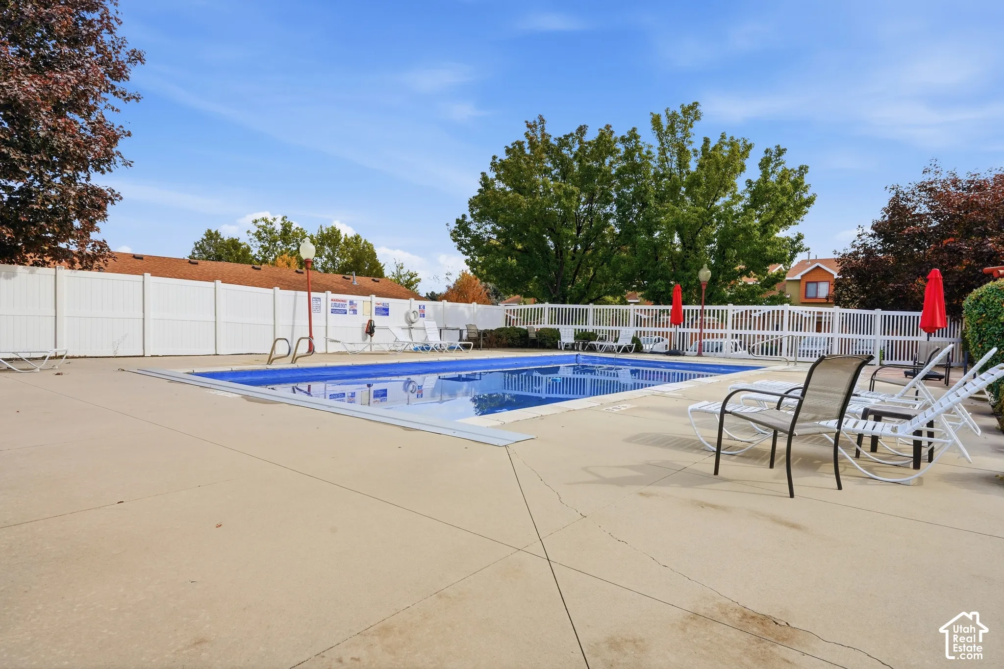 Outdoor swimming pool featuring a concrete deck and perimeter privacy fencing