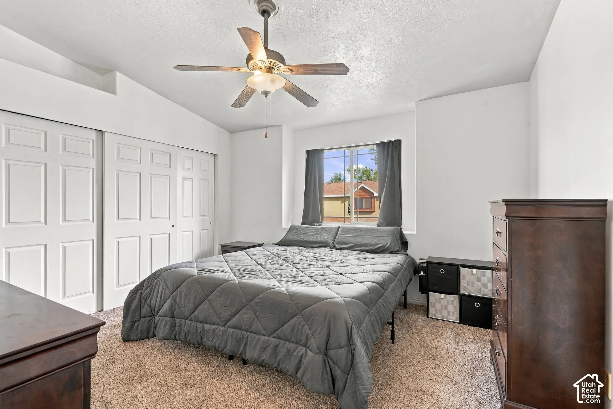 Bedroom featuring a vaulted ceiling, ceiling fan with integrated lighting, neutral wall-to-wall carpeting, and sliding panel closet doors