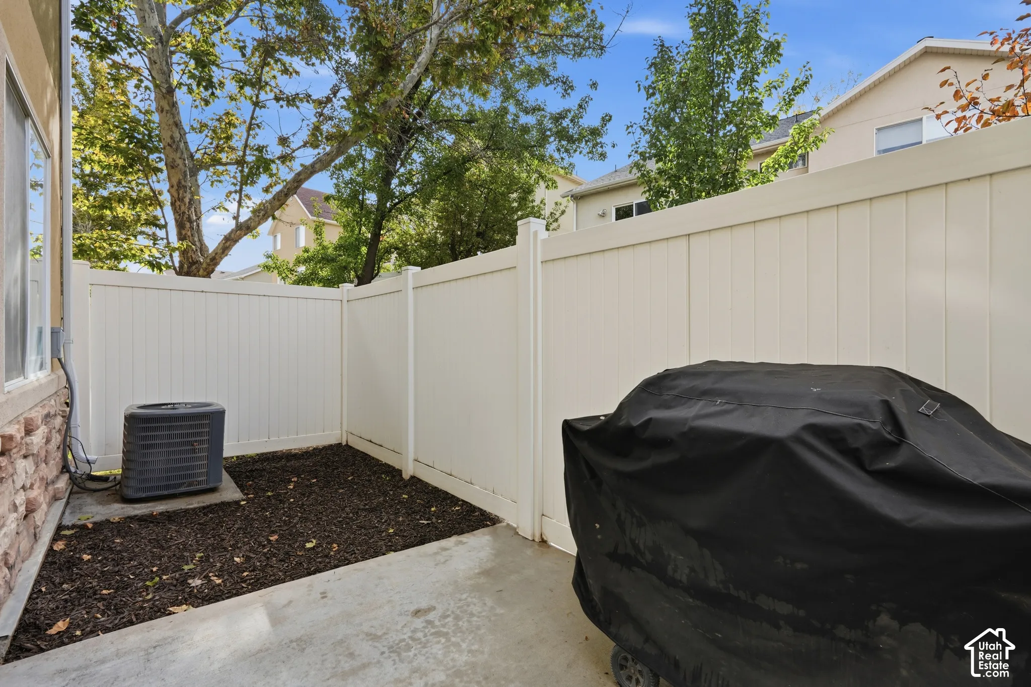 Rear patio featuring a concrete slab, mulch ground cover, and a full-height vinyl privacy fence