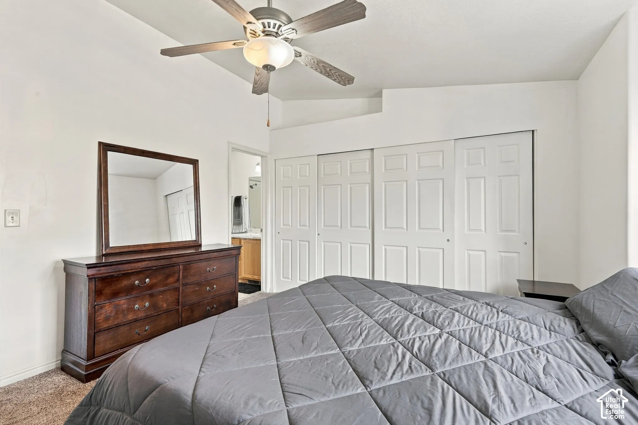 Vaulted ceilings, ceiling fan with integrated lighting, and expansive wall-to-wall closets with paneled sliding doors