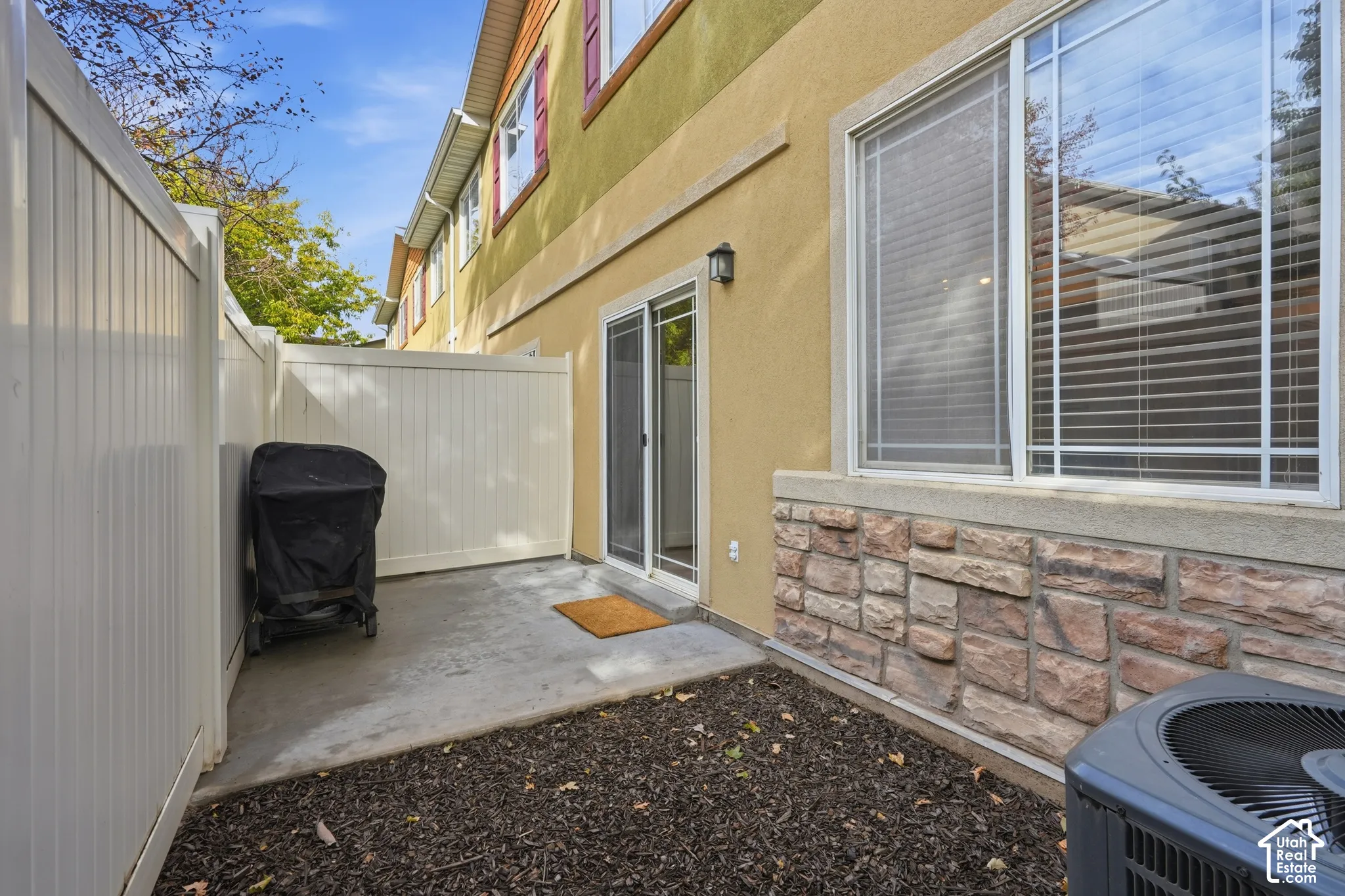 Private patio featuring a concrete surface, stone veneer siding, sliding glass door, and vinyl privacy fencing