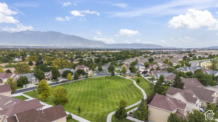 Aerial perspective featuring open green space, paved pathways, mature trees, and a mountain range backdrop