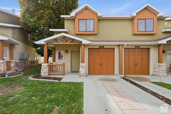 Multi-unit exterior featuring dual-tone siding, gabled dormers, decorative post-and-beam front porch detailing, stone-accented columns, and attached tandem-style garage doors