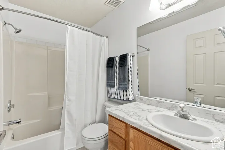 Bathroom featuring a vanity with a stone-patterned countertop, an oval drop-in sink, wooden cabinetry, and a full-width wall mirror