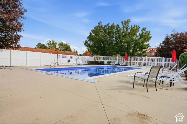 Outdoor swimming pool featuring a concrete deck and perimeter privacy fencing