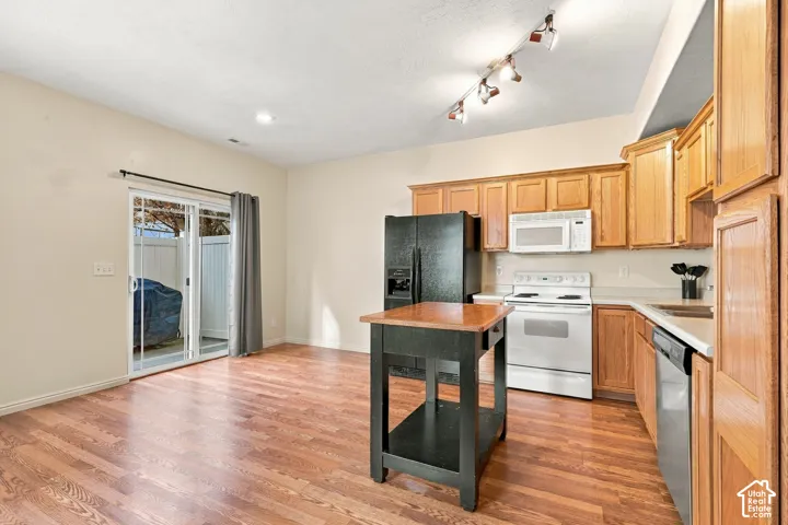Kitchen featuring wood-finish cabinetry, neutral countertops, wood-finish flooring, adjustable track lighting, and a sliding glass door