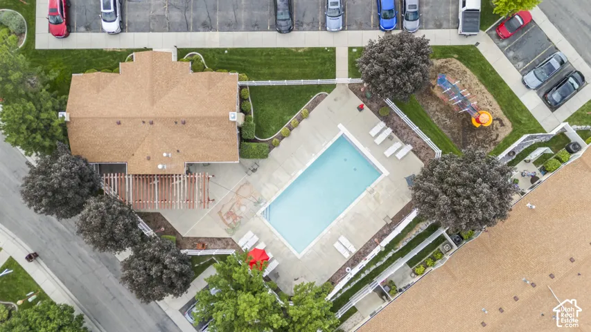 Aerial view of the community area featuring an outdoor swimming pool, concrete pool deck, wooden pergola, and playground