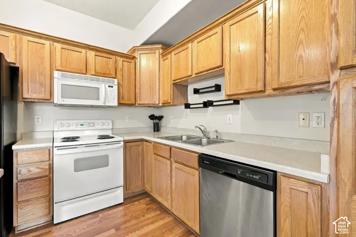 Kitchen featuring natural-finish wood cabinetry, solid-surface countertops, white electric range, over-the-range microwave, and stainless steel dishwasher