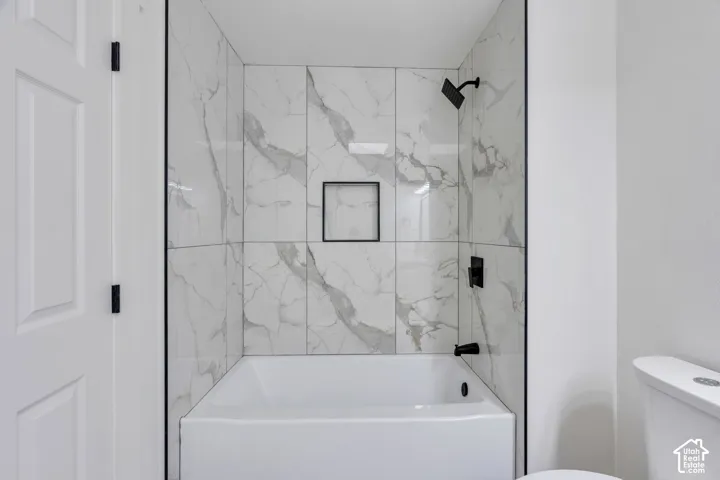 Shower-tub combination featuring large-format patterned wall tile, matte black plumbing fixtures, a built-in recessed niche, and black metal trim