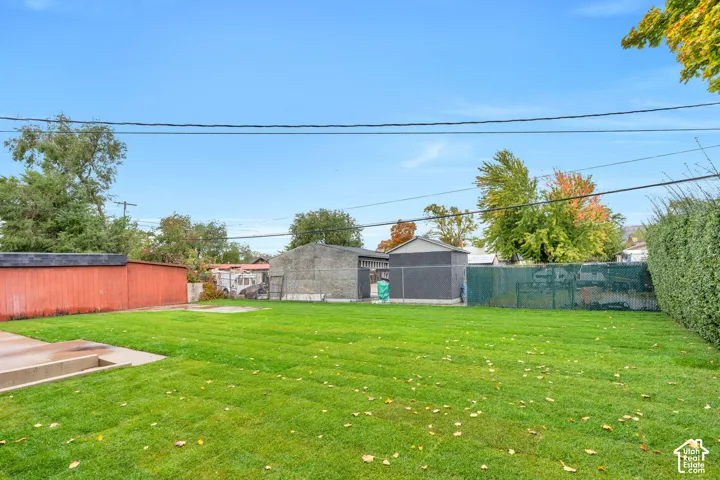 Expansive backyard featuring a level lawn, concrete patio, detached structure, and perimeter fencing
