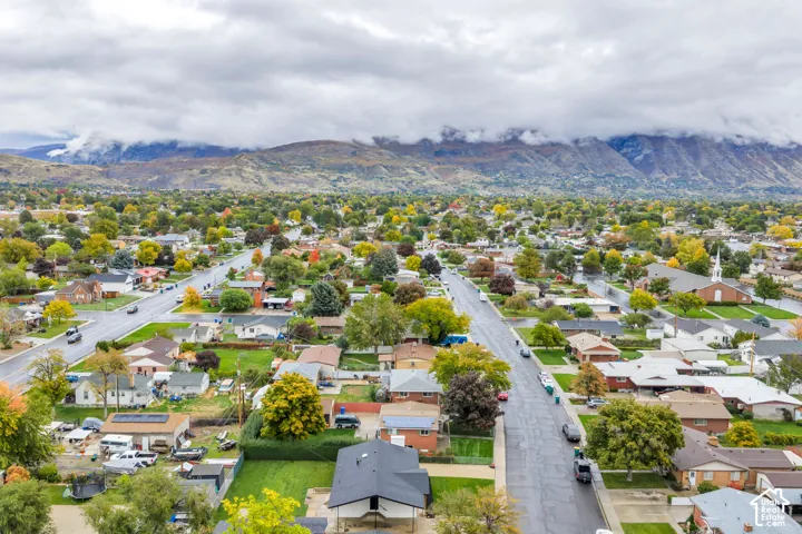 Aerial perspective featuring expansive mountain range backdrop and mature trees within a suburban landscape