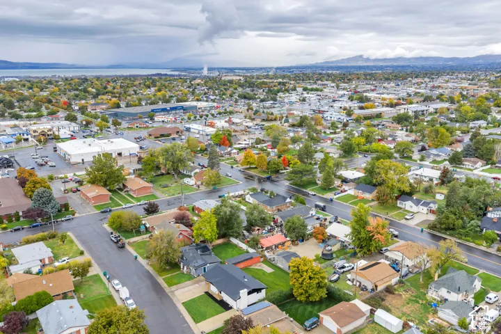 Aerial perspective featuring expansive residential neighborhood, mature trees, and mountainous horizon