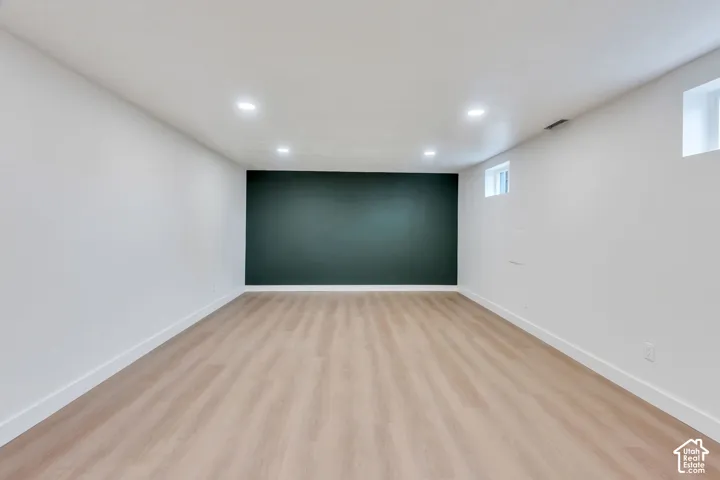 Neutral-toned wood-finish flooring, recessed lighting, and a dark-toned accent wall