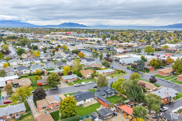 Aerial perspective of residential neighborhood featuring mature trees, paved streets, and a mountain and water backdrop