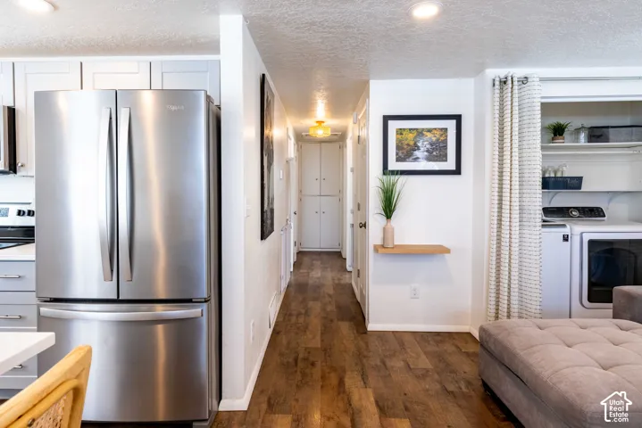 Stainless steel French-door refrigerator, wood-finish flooring, recessed lighting, and integrated laundry area with overhead storage shelving