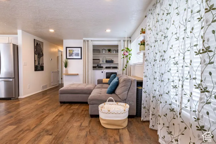 Living space featuring wood-finish flooring, recessed lighting, and a built-in laundry closet with integrated shelving