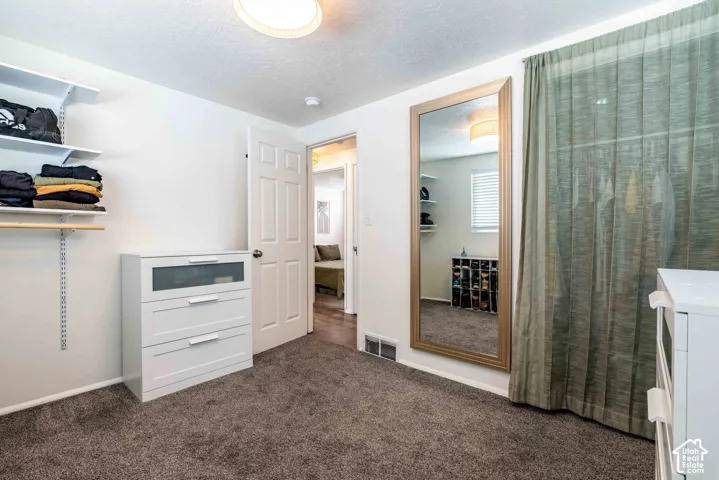 Wall-mounted open shelving, wall-to-wall carpeting, and a full-length wall mirror with a wood-finish frame