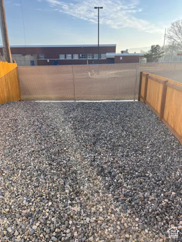 Low-maintenance gravel yard enclosed by wood-panel fencing and chain-link perimeter