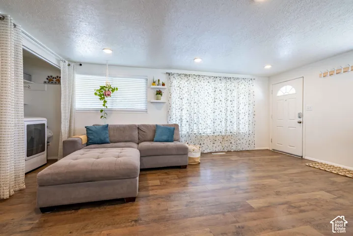Wood-finish flooring, recessed lighting, white panel entry door, and integrated wall shelving